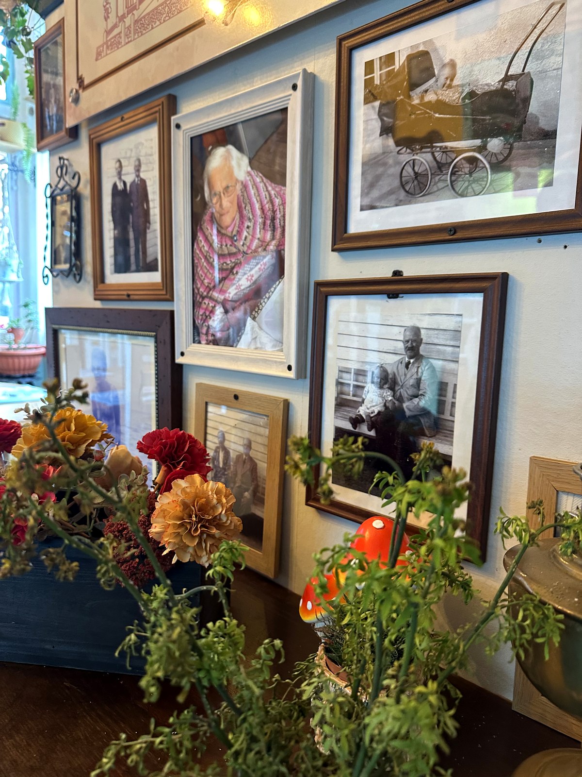 Galería de fotografías familiares antiguas conservadas en la casa, junto a un arreglo de flores